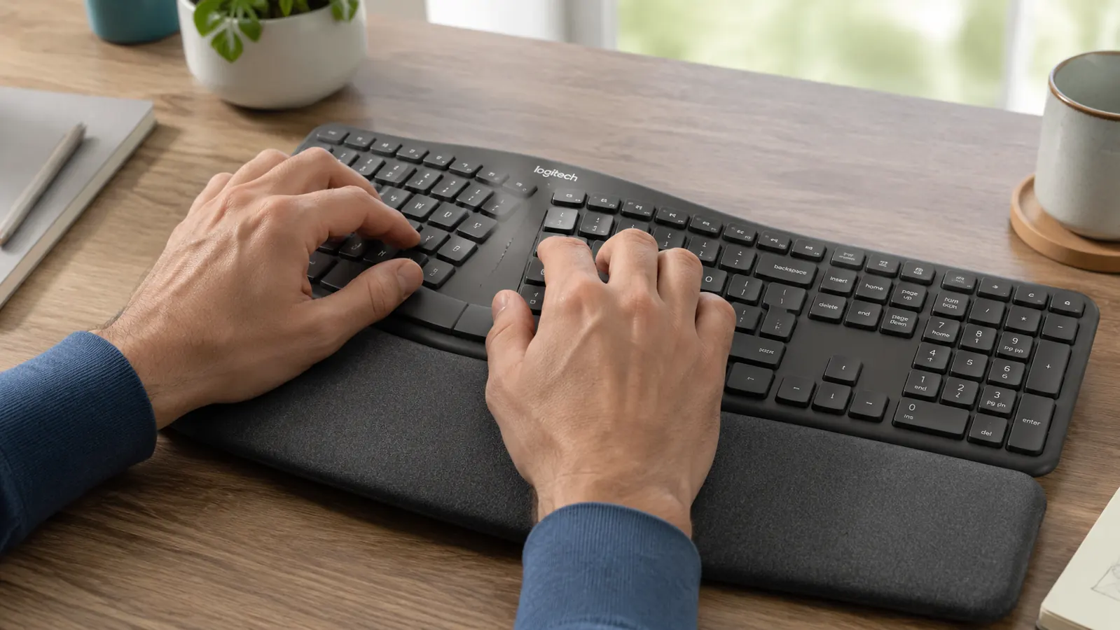 Hands resting naturally on the Logitech K860 split keyboard with wrist pad engaged