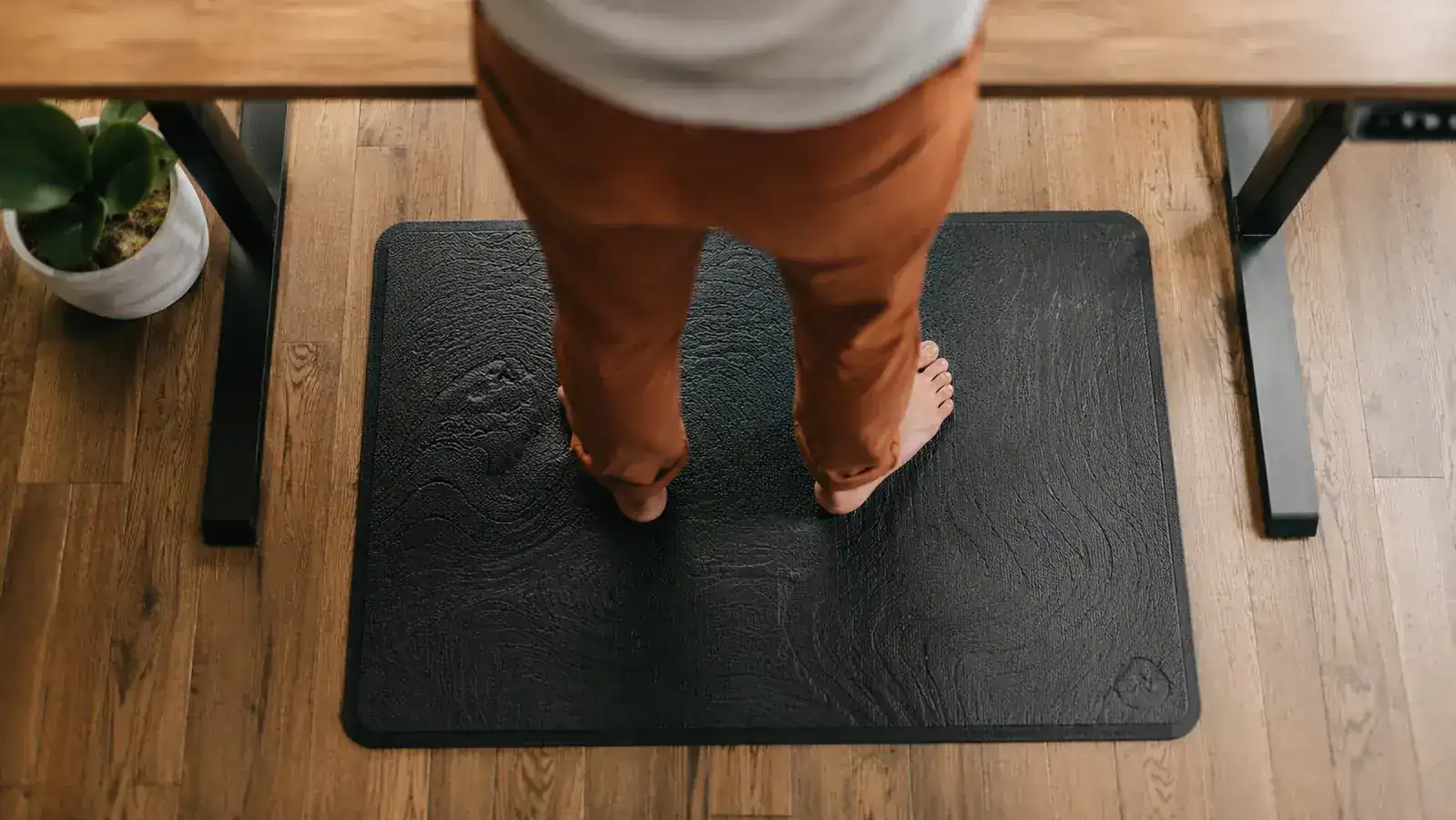 Home office worker in socks standing confidently on a contoured mat at a standing desk, posture relaxed and upright