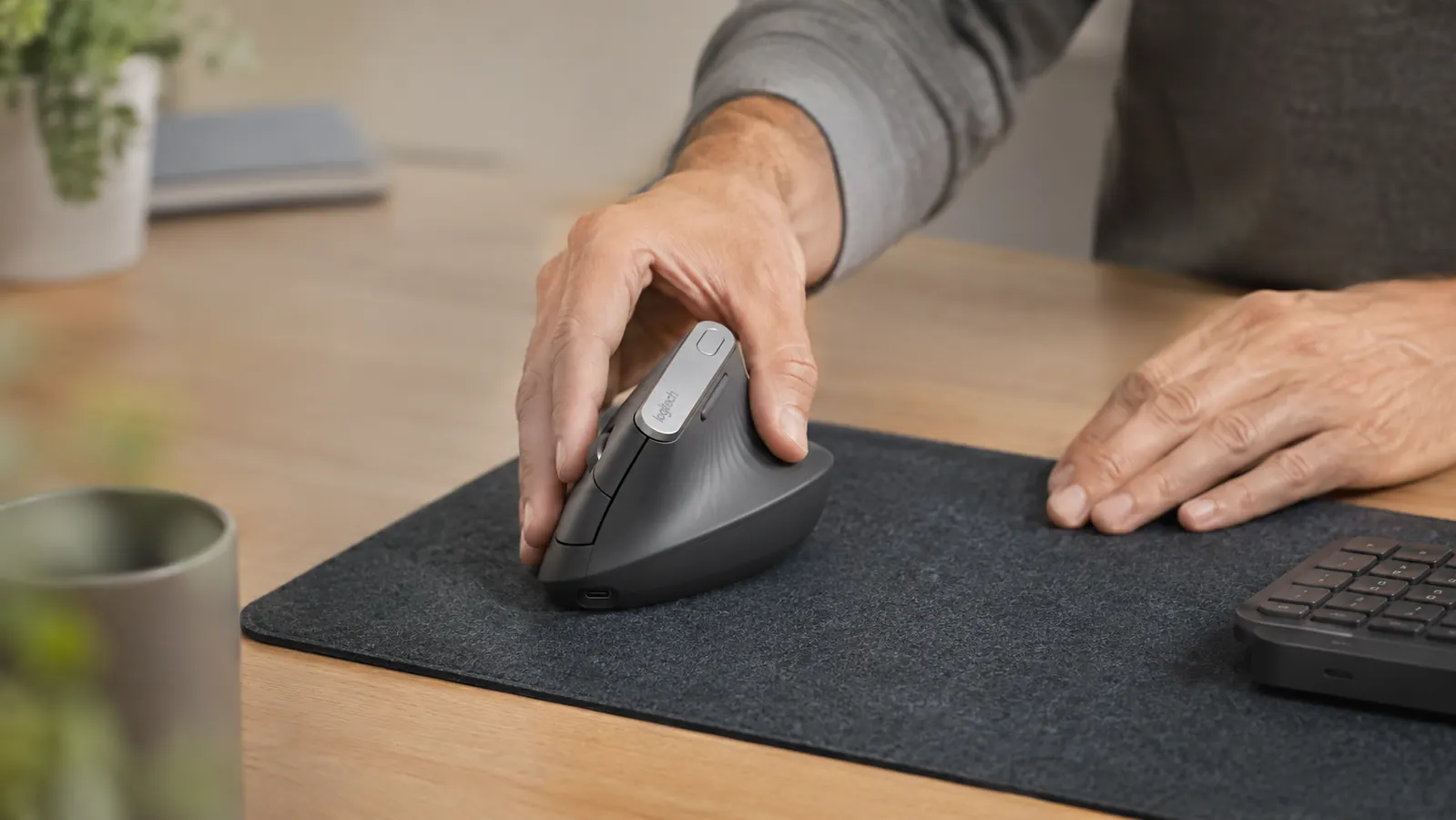 Hand resting naturally on a Logitech MX Vertical mouse on a desk pad, showing the handshake grip angle