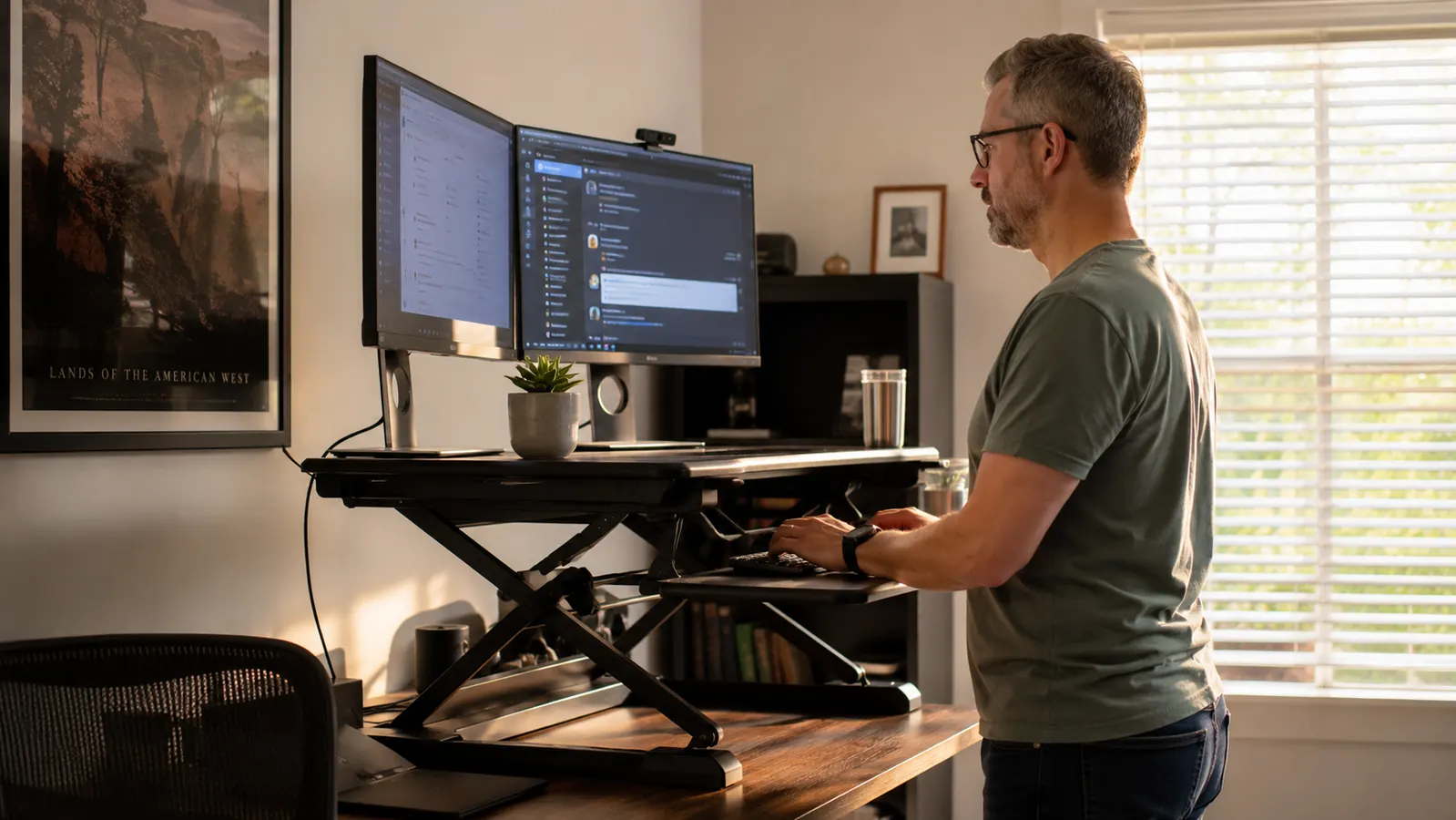 Woman glancing away from her monitor at a standing desk converter, looking comfortable and at ease mid-workday